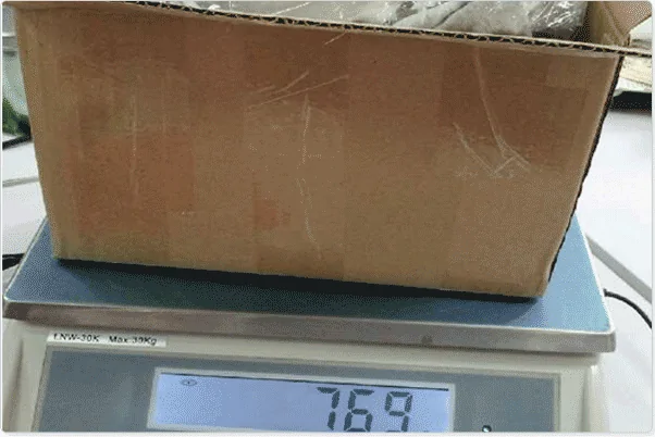 A taped cardboard parcel weighed on a digital scale showing 769
