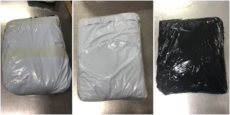 Three soft parcels in grey and black plastic mailers on a warehouse table